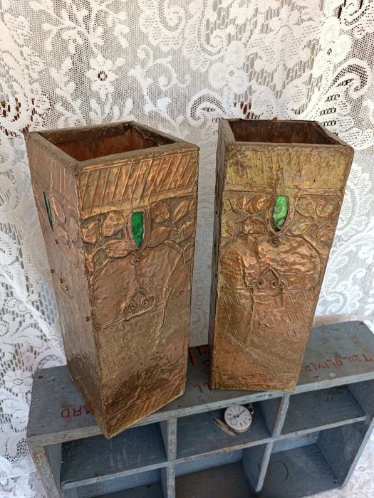French Brocante - For Sale - Pair of Repousse Metal Clad Wood VasesDescription: <p>Dating to the early 1900's these striking vases have both elements of Arts and Crafts and Art Nouveau design</p>

<p>The base is a light weight wood and over this the decorative layer of repousse metal has been folded and pinned into place with green glass cabouchons inserted on all four sides of both vases</p>

<p>We aren't really sure what the metal is, it is very finely beaten, it could be copper with a patination to look bronzed</p>

<p>Three of the glass inserts have a small amount of damage</p>

<p>They are 11cm square and 32cm high, they aren't heavy for shipping, just 1.3kg </p>
